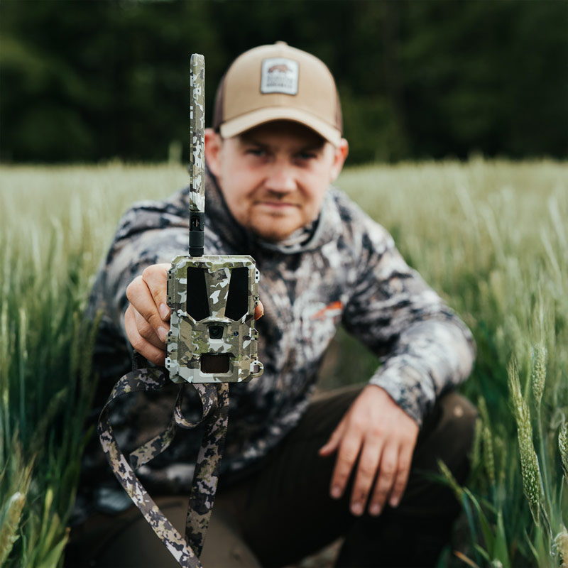 Die Bresser Modern Hunter Mini Wildkamera Hunter 4G wird von einem Jäger in der Hand gehalten und in die Kamera präsentiert
