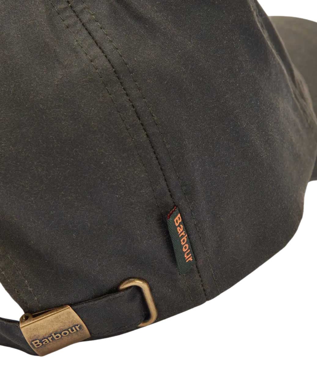 Detailansicht der Barbour Wax Cap in dunklem Oliv auf den Metallverschluss und das Marken-Fähnchen