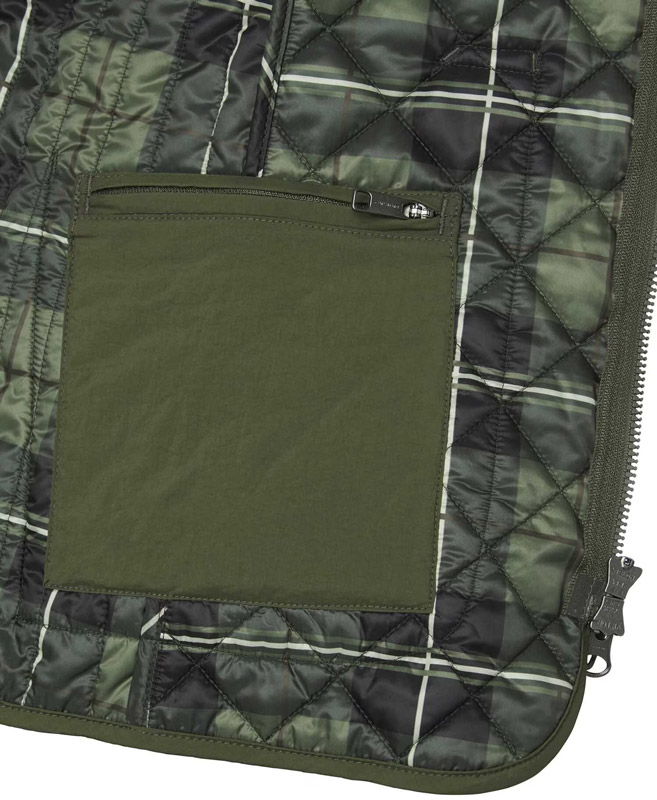 Die Innentasche der Chevalier Weste Dunsley Quilted in Detailansicht, die Tasche hat einen Reißverschluss und ist in derselben dunkelgrünen Farbe wie die Weste selbst, Innenfutter der Weste mit grünem Karomuster